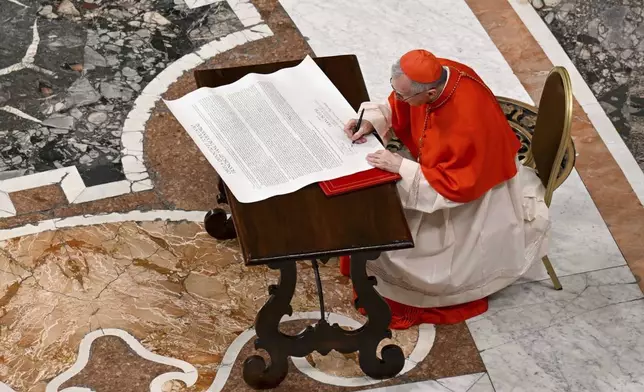 Cardinal Camerlengo Kevin Joseph Farrel signs the official deed of late Pope Francis before closing his casket in St. Peter's Basilica at the Vatican Friday, April 25, 2025. (Vatican Media via AP)