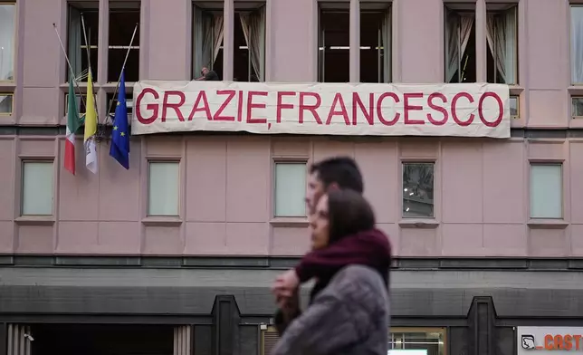 People set up a banner on a building near the Santa Maria Maggiore Basilica, where the late Pope Francis will be buried, in Rome, Thursday, April 24, 2025. (AP Photo/Andreea Alexandru)