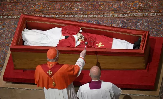 Cardianal Camerlengo Kevin Joseph Farrel asperges the body of late Pope Francis with holy water before closing his casket in St. Peter's Basilica at the Vatican Friday, April 25, 2025. (Vatican Media via AP)
