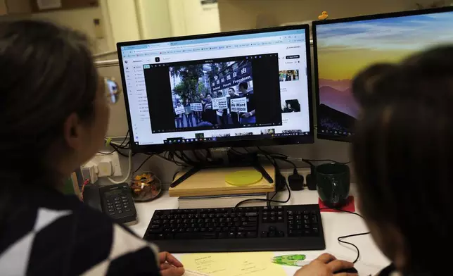 Emily Lau, former chairperson of the Democratic Party, right, looks through old photos with a staffer at the Democratic Party's office in Prince Edward in Hong Kong on April 2, 2025. (AP Photo/May James)