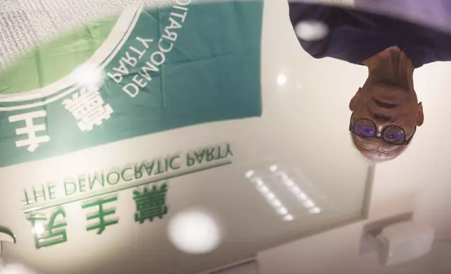 Yeung Sum, the founding member of the Democratic Party, is reflected on a glass surface during an interview at the Democratic Party's office in Prince Edward in Hong Kong on April 2, 2025. (AP Photo/May James)