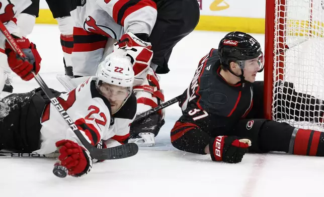 New Jersey Devils' Brett Pesce (22) moves the puck away from the crease with Carolina Hurricanes' Andrei Svechnikov (37) nearby during the second period of Game 2 of an NHL hockey Stanley Cup first-round playoff series in Raleigh, N.C., Tuesday, April 22, 2025. (AP Photo/Karl DeBlaker)
