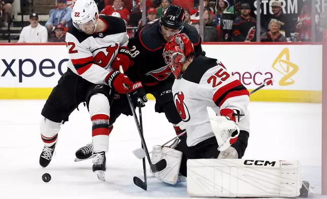 Carolina Hurricanes' William Carrier (28) battles for the pic between New Jersey Devils' Brett Pesce (22) and goaltender Jacob Markstrom (25) during the second period of Game 2 of an NHL hockey Stanley Cup first-round playoff series in Raleigh, N.C., Tuesday, April 22, 2025. (AP Photo/Karl DeBlaker)