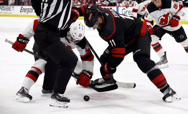 Carolina Hurricanes' Jordan Staal (11) battles for the puck with New Jersey Devils' Nico Hischier (13) during a face-off during the third period of Game 2 of an NHL hockey Stanley Cup first-round playoff series in Raleigh, N.C., Tuesday, April 22, 2025. (AP Photo/Karl DeBlaker)