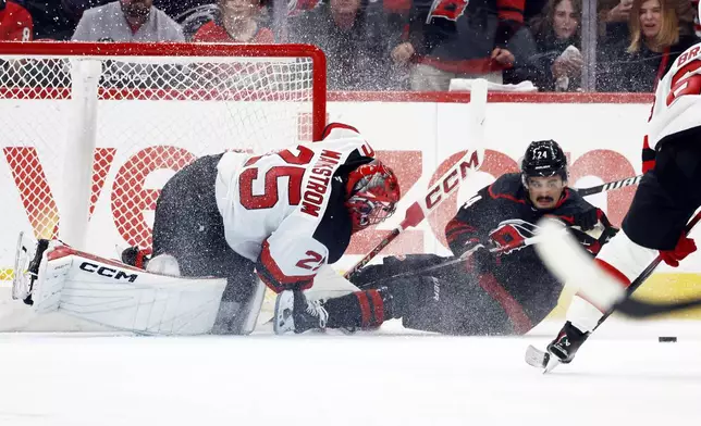 Carolina Hurricanes' Seth Jarvis (24) crashes into New Jersey Devils goaltender Jacob Markstrom (25) during the first period of Game 2 of an NHL hockey Stanley Cup first-round playoff series in Raleigh, N.C., Tuesday, April 22, 2025. (AP Photo/Karl DeBlaker)