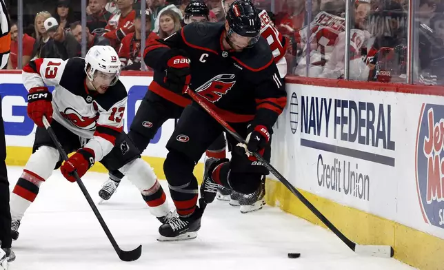 Carolina Hurricanes' Jordan Staal (11) controls the puck with New Jersey Devils' Nico Hischier (13) nearby during the third period of Game 2 of an NHL hockey Stanley Cup first-round playoff series in Raleigh, N.C., Tuesday, April 22, 2025. (AP Photo/Karl DeBlaker)