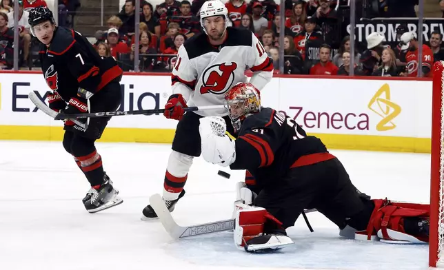 New Jersey Devils' Stefan Noesen (11) watches the puck go wide off Carolina Hurricanes goaltender Frederik Andersen (31) with Dmitry Orlov (7) nearby during the first period of Game 1 of an NHL hockey Stanley Cup first-round playoff series in Raleigh, N.C., Sunday, April 20, 2025. (AP Photo/Karl DeBlaker)