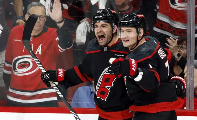 Carolina Hurricanes' Jordan Martinook, left, celebrates his goal with Dmitry Orlov (7) during the second period of Game 2 of an NHL hockey Stanley Cup first-round playoff series against the New Jersey Devils in Raleigh, N.C., Tuesday, April 22, 2025. (AP Photo/Karl DeBlaker)