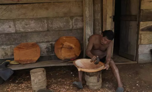 Pedro Chami carves a gold-panning dish made of wood in Villa Caleta, a community in Panama that used to benefit economically by being on the route migrants took after crossing the Darien Gap on their way north to the U.S., Monday, April 7, 2025. (AP Photo/Matias Delacroix)