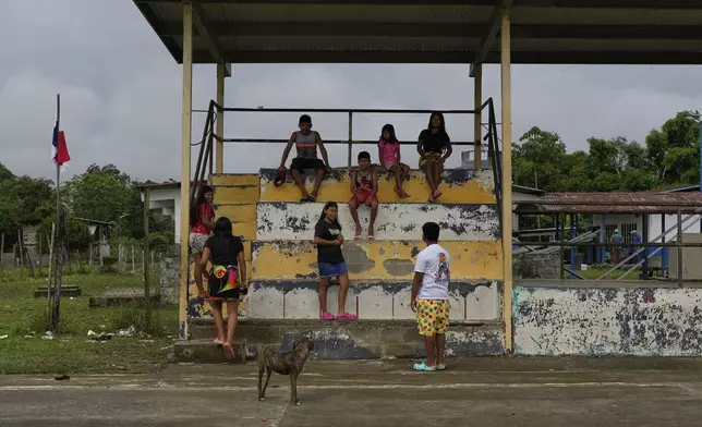 Youths hang out at a ball court in Villa Caleta, a community in Panama that used to benefit economically by being on the route migrants took after crossing the Darien Gap on their way north to the U.S., Monday, April 7, 2025. (AP Photo/Matias Delacroix)