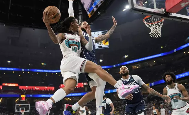 Memphis Grizzlies guard Ja Morant (12)- passes the ball around Dallas Mavericks forward Caleb Martin, right, during the first half of an NBA play-in tournament basketball game Friday, April 18, 2025, in Memphis, Tenn. (AP Photo/George Walker IV)
