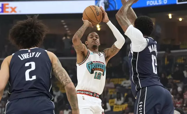 Memphis Grizzlies guard Ja Morant (12) shoots the ball past Dallas Mavericks center Dereck Lively II (2) and forward Naji Marshall, right, during the first half of an NBA play-in tournament basketball game Friday, April 18, 2025, in Memphis, Tenn. (AP Photo/George Walker IV)