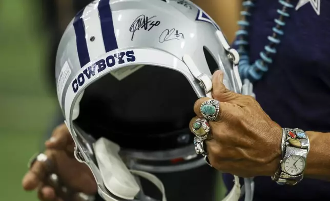 A Dallas Cowboys fan holds an autographed helmet during a Cowboys NFL football draft party in Frisco, Texas, Thursday, April 24, 2025. (AP Photo/Gareth Patterson)