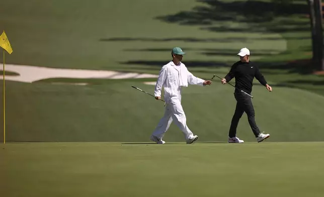 Rory McIlroy, of Northern Ireland, hand his club to his caddie, Harry Diamond, left, on the 10th green during a practice round at the Masters golf tournament, Tuesday, April 8, 2025, in Augusta, Ga. (AP Photo/Matt Slocum)