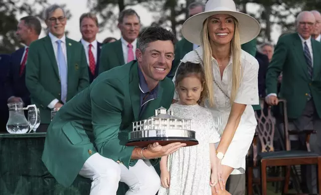 Rory McIlroy, of Northern Ireland, with his wife Erica Stoll, and daughter Poppy, holds the trophy after winning the Masters golf tournament, Sunday, April 13, 2025, in Augusta, Ga. (AP Photo/David J. Phillip)