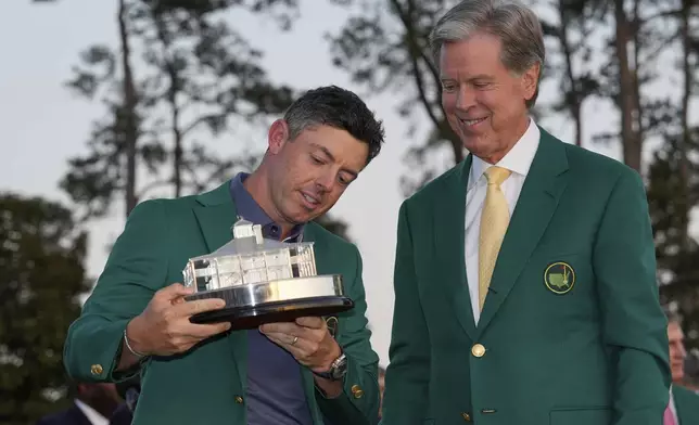 Winner Rory McIlroy, of Northern Ireland, holds the trophy with Masters Chaiman Fred Ridley, right, at the Masters golf tournament, Sunday, April 13, 2025, in Augusta, Ga. (AP Photo/David J. Phillip)