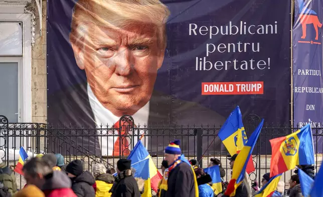 FILE - Supporters of Calin Georgescu, the winner of Romania's first round of presidential election, annulled by the Constitutional Court, march past a large banner showing U.S. President Donald Trump that reads "Republicans for Freedom" during a protest in Bucharest, Romania, Saturday, Feb. 22, 2025. (AP Photo/Andreea Alexandru, File)