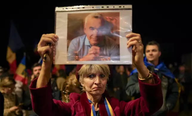 FILE - A woman holds a portrait of Calin Georgescu during a protest after Romania's Constitutional Court upheld a ban on his candidacy in the presidential election rerun, in Bucharest, Romania, Tuesday, March 11, 2025. (AP Photo/Vadim Ghirda. File)