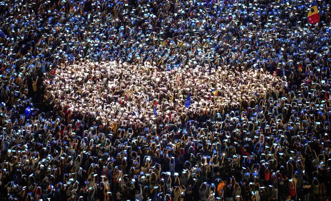 FILE - People shine lights behind coloured papers attempting to make a heart shape during a pro-European rally, joined by thousands, to counter what the organizers described as a "wave of sovereignism and ultranationalism", outside the government headquarters in Bucharest, Romania, Saturday, March 15, 2025. (AP Photo/Andreea Alexandru, File)
