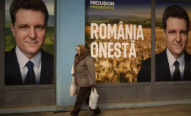 A woman walks by posters of Nicusor Dan, the mayor of Bucharest and presidential candidate in the upcoming May elections in Bucharest, Romania, Friday, March 28, 2025. (AP Photo/Vadim Ghirda)