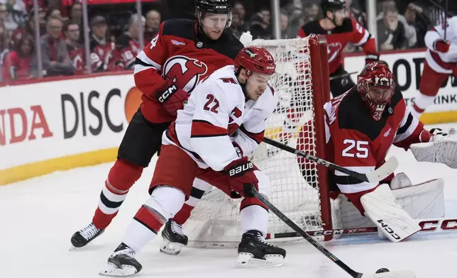 Carolina Hurricanes' Logan Stankoven, center, brings the puck around the net as New Jersey Devils goaltender Jacob Markstrom, right, and Dennis Cholowski look on during the first period of Game 4 of an NHL hockey first-round series, Sunday, April 27, 2025, in Newark, N.J. (AP Photo/Seth Wenig)