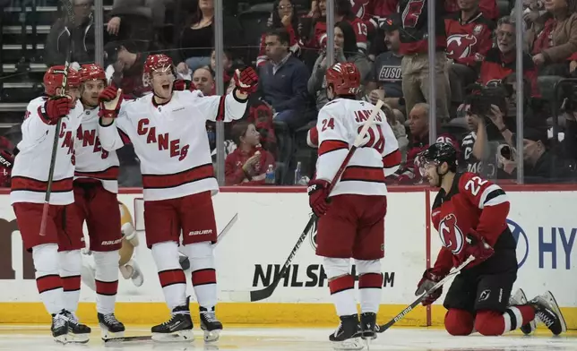 Carolina Hurricanes' Andrei Svechnikov, third from left, celebrates his goal with teammates as New Jersey Devils Brett Pesce, right, looks on during the second period of Game 4 of an NHL hockey first-round series, Sunday, April 27, 2025, in Newark, N.J. (AP Photo/Seth Wenig)