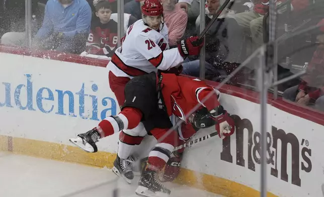 Carolina Hurricanes' Sean Walker, left, hits New Jersey Devils' Paul Cotter during the first period of Game 4 of an NHL hockey first-round series, Sunday, April 27, 2025, in Newark, N.J. (AP Photo/Seth Wenig)
