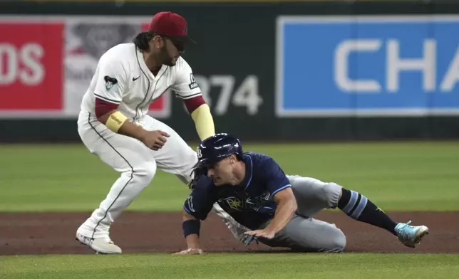 Tampa Bay Rays' Jake Mangum, right, gets tagged out by Arizona Diamondbacks third base Eugenio Suárez while trying to advance to third base in the fifth inning during a baseball game, Tuesday, April 22, 2025, in Phoenix. (AP Photo/Rick Scuteri)