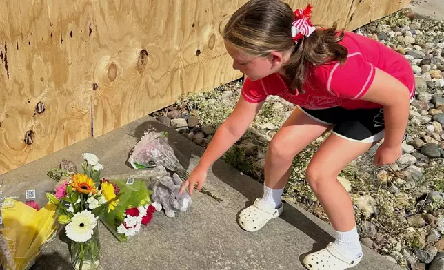 Madison Foster, 10, points out the flowers and plush bunny she left for the victims who were killed Monday, when a car barreled through a building used for an after-school camp in Chatham, Ill., on Tuesday, April 29, 2025. (AP Photo/John O'Connor)