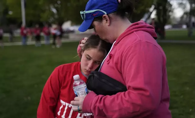 Heather Glessner comforts her 9-year-old daugher Coralie at a vigil for three young children and a teenager who were killed when a car barreled through a building used for an after-school camp, Tuesday, April 29, 2025, in Chatham, Ill. (AP Photo/Erin Hooley)