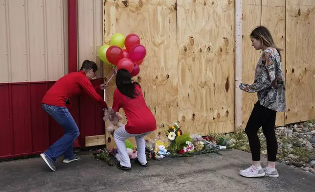 People leave balloons at the scene for victims killed when a car barreled through a building used for an after-school camp, Tuesday, April 29, 2025, in Chatham, Ill. (AP Photo/Erin Hooley)
