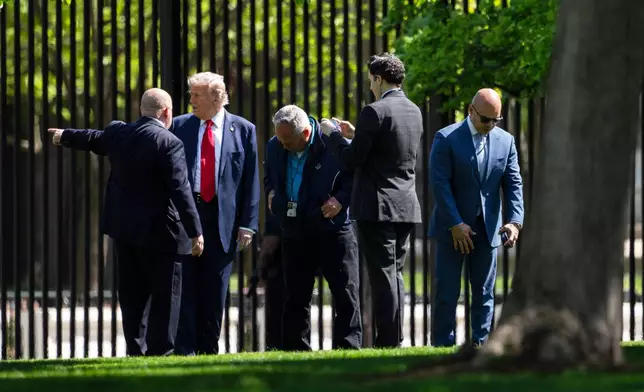 President Donald Trump, second from left, stands along the fence line at the North Lawn of the White House in Washington, Wednesday, April 23, 2025, in Washington. (AP Photo/Mark Schiefelbein)