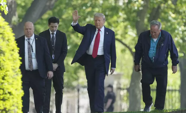President Donald Trump, center, waving as he walks with staff members on the North Lawn of the White House in Washington, Wednesday, April 23, 2025. (AP Photo/Mark Schiefelbein)