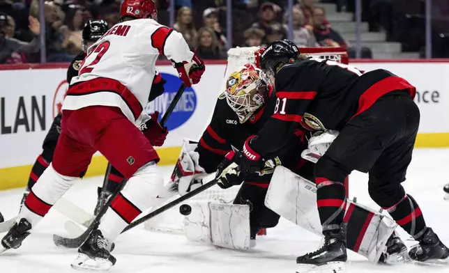 Ottawa Senators goaltender Linus Ullmark, second from right, stretches for a pad-save on a shot by Carolina Hurricanes center Jesperi Kotkaniemi (82) during first-period NHL hockey game action in Ottawa, Ontario, Thursday, April 17, 2025. (Spencer Colby/The Canadian Press via AP)