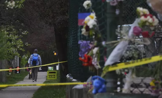 A sign for a federal election voting center stands near the memorial for the victims of a driver who rammed into a crowd during a Filipino heritage festival in Vancouver, British Columbia, Monday, April 28, 2025. (AP Photo/Lindsey Wasson)