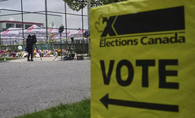 A voting sign stands near a memorial for victims after a vehicle drove into a crowd during a Filipino heritage festival in Vancouver, British Columbia, Monday, April 28, 2025. (AP Photo/Lindsey Wasson)