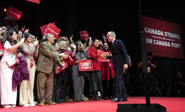 Canadian Prime Minister Mark Carney, right, arrives on stage at his campaign headquarters after the Liberal Party won the Canadian election in Ottawa on Tuesday, April 29, 2025. (Justin Tang/The Canadian Press via AP)