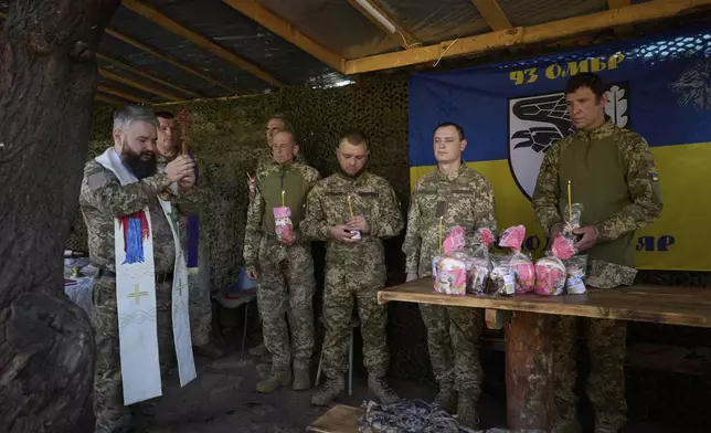 In this photo provided by Ukraine's 93rd Kholodnyi Yar Separate Mechanized Brigade press service, Ukrainian servicemen attend an Easter service on their position in the Donetsk region, Ukraine, Sunday, April 20, 2025. (Mykola Oliinyk/Ukraine's 93rd Mechanized Brigade via AP)