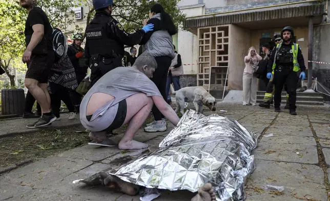 A man checks the dead body of his neighbor near a multi-story building damaged by a Russian strike on residential neighborhood in Zaporizhzhia, Ukraine, on Tuesday, April 22, 2025. (AP Photo/Kateryna Klochko)