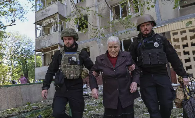 Police officers evacuate a woman from a multi-storey building damaged by a Russian strike on residential neighbourhood in Zaporizhzhia, Ukraine, on Tuesday, April 22, 2025. (AP Photo/Kateryna Klochko)
