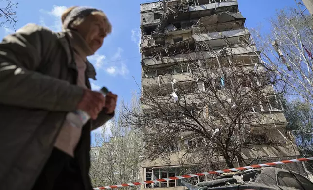 A woman walks in front of a multi-storey building damaged by a Russian strike on a residential neighbourhood in Zaporizhzhia, Ukraine, on Tuesday, April 22, 2025. (AP Photo/Kateryna Klochko)