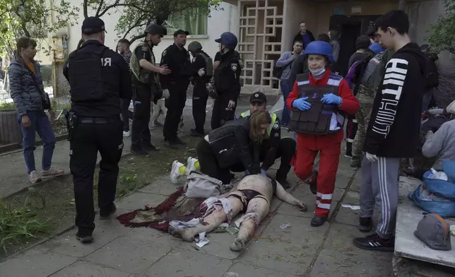 EDS NOTE: GRAPHIC CONTENT - People try to give first aid to an injured civilian at a residential building damaged by a Russian strike in Zaporizhzhia, Ukraine, Tuesday, April 22, 2025. (AP Photo/Andriy Andriyenko)