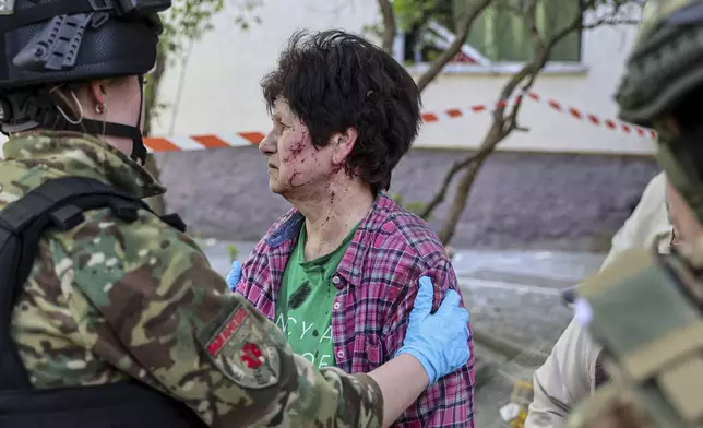 A police officer comforts an injured woman near a multi-storey building damaged by a Russian strike on residential neighbourhood in Zaporizhzhia, Ukraine, on Tuesday, April 22, 2025. (AP Photo/Kateryna Klochko)