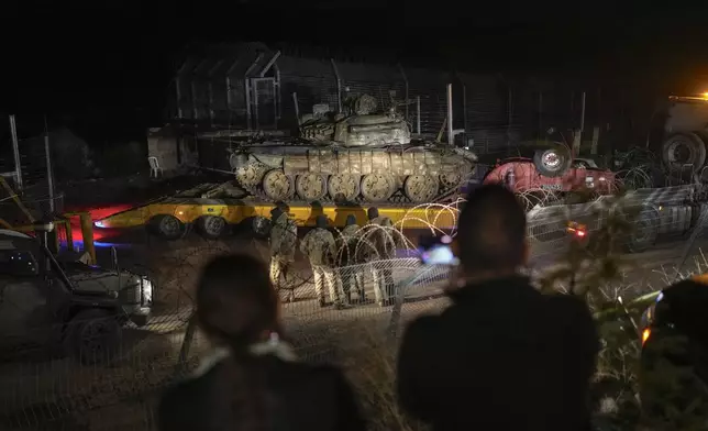 FILE - An Israeli truck carries a Syrian tank from the buffer zone near the so-called Alpha Line that separates the Israeli-controlled Golan Heights from Syria, viewed from the town of Majdal Shams, Dec. 21, 2024. (AP Photo/Matias Delacroix, File)