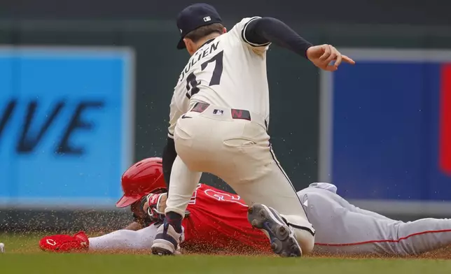 Minnesota Twins second baseman Edouard Julien (47) tags out Los Angeles Angels' Luis Rengifo, bottom on a stolen base-attempt in the fifth inning of a baseball game Sunday, April 27, 2025, in Minneapolis. (AP Photo/Bruce Kluckhohn)