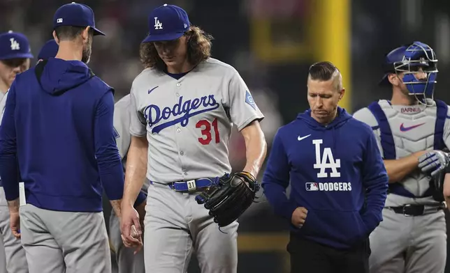 Los Angeles Dodgers starting pitcher Tyler Glasnow (31) leaves the mound followed by a team staff member after suffering an unknown injury in the fifth inning of a baseball game against the Texas Rangers in Arlington, Texas, Sunday, April 20, 2025. (AP Photo/Tony Gutierrez)