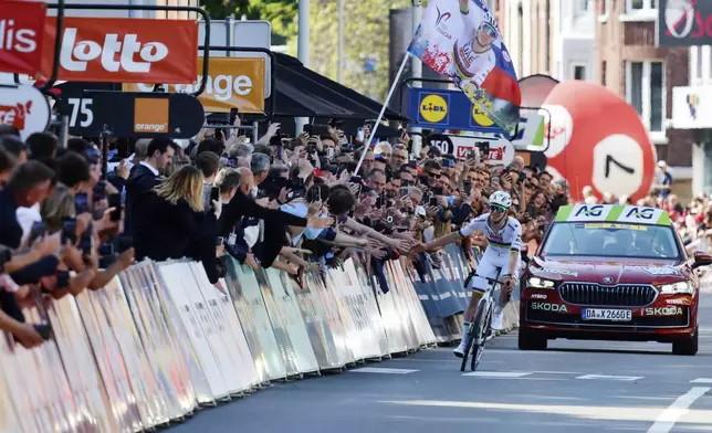 Slovenia's Tadej Pogacar of the UAE Team Emirates URG team greets the crowd as he prepares to cross the finish line to win the Belgian cycling classic and UCI World Tour race Liege Bastogne Liege, in Liege, Belgium, Sunday, April 27, 2025. (AP Photo/Geert Vanden Wijngaert)