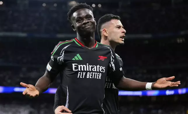 Arsenal's Bukayo Saka celebrates with Gabriel Martinelli, right, after scoring the opening goal during the Champions League quarterfinals second leg soccer match between Real Madrid and Arsenal at the Santiago Bernabeu stadium in Madrid, Wednesday, April 16, 2025. (AP Photo/Manu Fernandez)