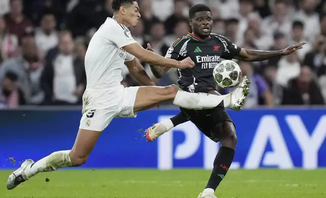 Real Madrid's Jude Bellingham, left, duels for the ball with Arsenal's Thomas Partey during the Champions League quarterfinals second leg soccer match between Real Madrid and Arsenal at the Santiago Bernabeu stadium in Madrid, Wednesday, April 16, 2025. (AP Photo/Bernat Armangue)