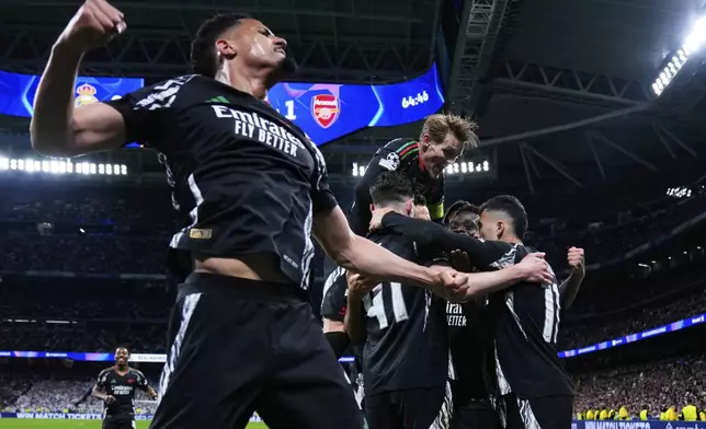 Arsenal players celebrate after Bukayo Saka, 2nd right, scored the opening goal during the Champions League quarterfinals second leg soccer match between Real Madrid and Arsenal at the Santiago Bernabeu stadium in Madrid, Wednesday, April 16, 2025. (AP Photo/Manu Fernandez)